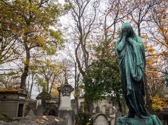 City of Immortals: Père-Lachaise Cemetery, Paris: New Book Celebrates the Rich and Beautiful History of the World’s Most Famous Cemetery A weathered statue stands among the tombstones in Pére Lachaise Cemetery