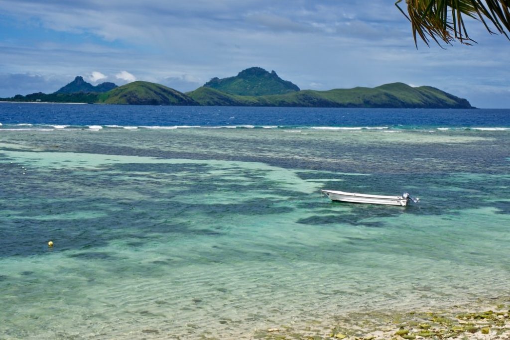 white wooden boat on sea near mountain