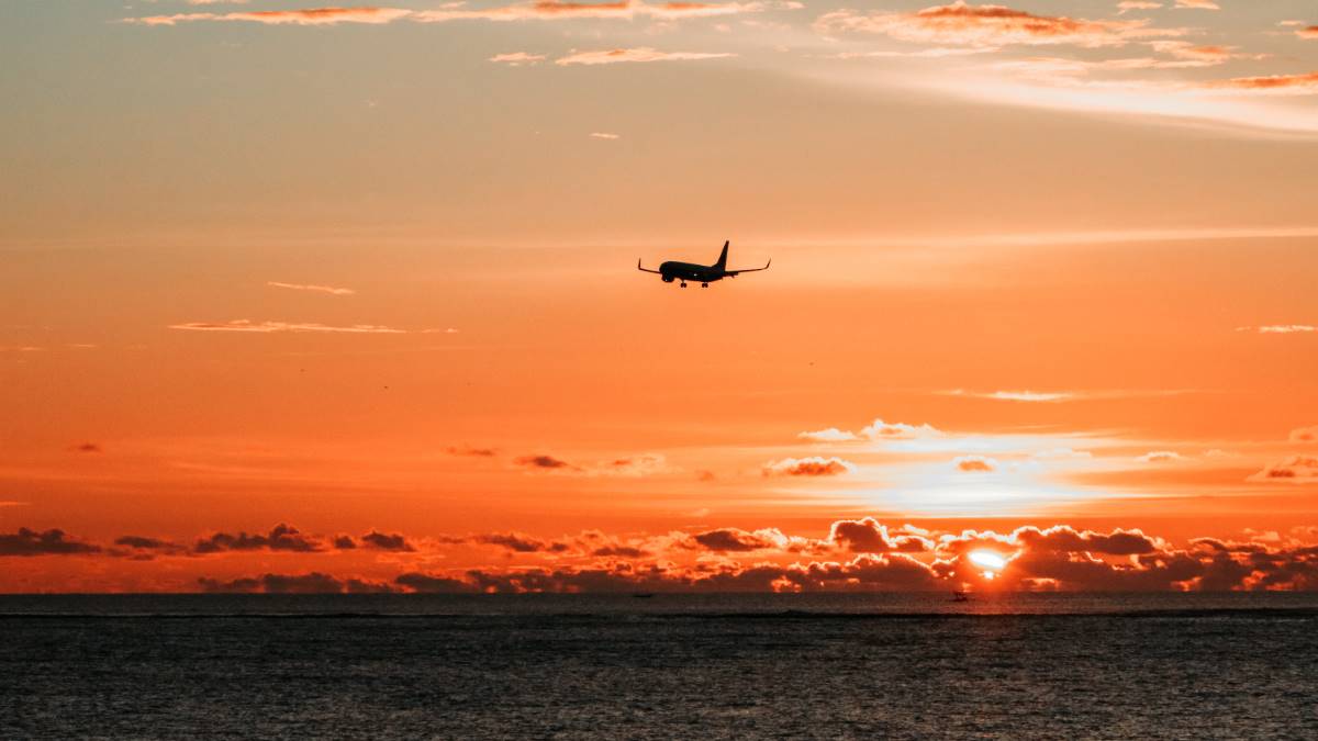 airplane flying off in the sunset