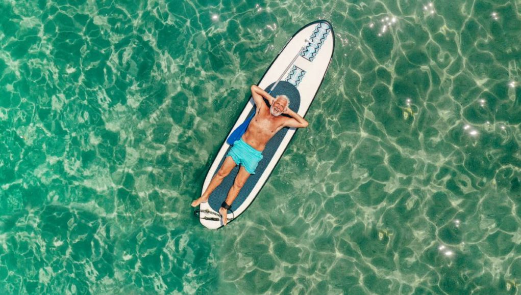 boomer man floating on a paddle board