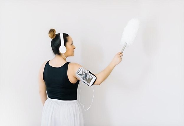 girl dusting a wall while listening to music