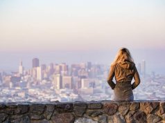 3 Undeniable Reasons Why Travel is Beneficial to Living a Good Life sitting on a wall looking a city
