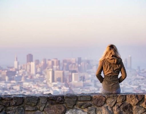 3 Undeniable Reasons Why Travel is Beneficial to Living a Good Life sitting on a wall looking a city