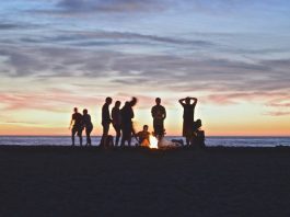 people standing around a fire pit at sunset