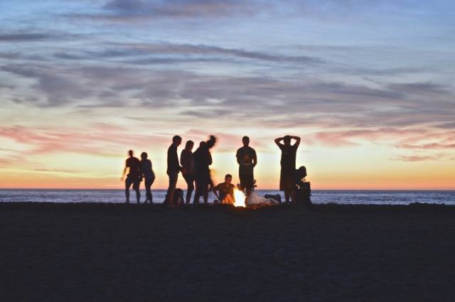 people standing around a fire pit at sunset