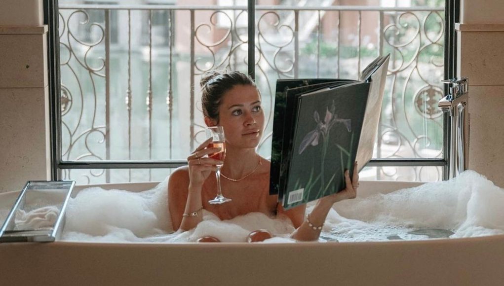 girl in a bubble bath reading a book