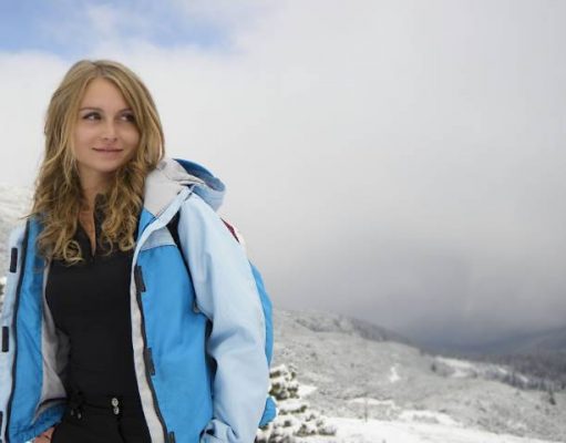 Top 5 Travel Gear You Need Most When Travelling To Colder Climates girl in winter with a blue ski jacket