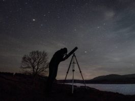 person llooking at the night sky through a telescope