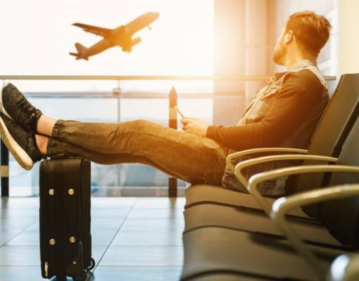 6 Mistakes to Avoid If You Want to Book Your Holiday Travel Online man sitting an airport watching a plane take off