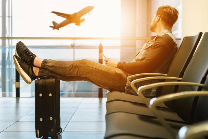 man sitting an airport watching a plane take off