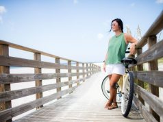 Dip your toes in Alabama’s Gulf Coast girl with a bicycle on a boardwalk in Alabama