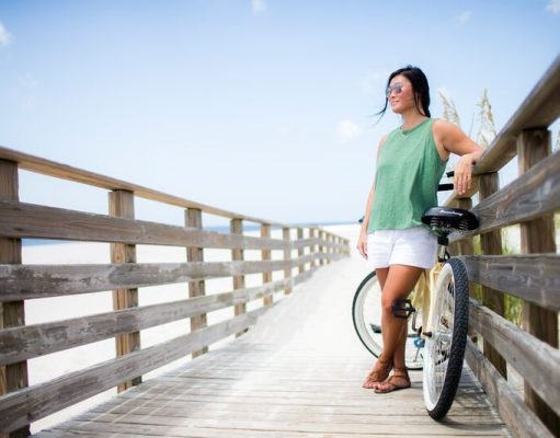 Dip your toes in Alabama’s Gulf Coast girl with a bicycle on a boardwalk in Alabama