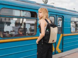 girl with a backpack waiting at a train station