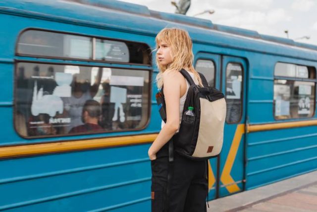 girl with a backpack waiting at a train station