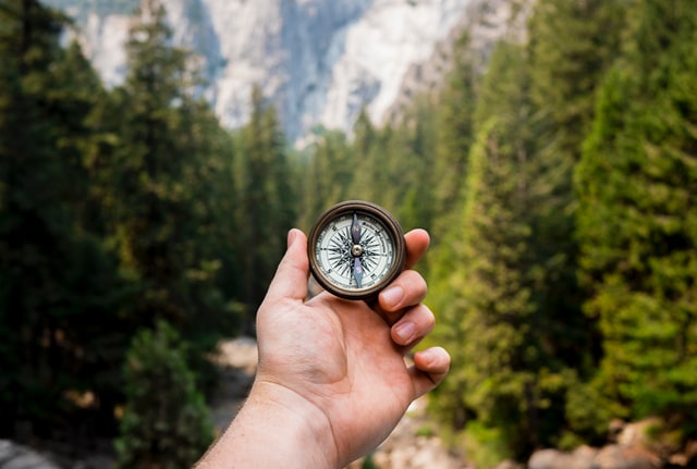 holding a compass in a forest