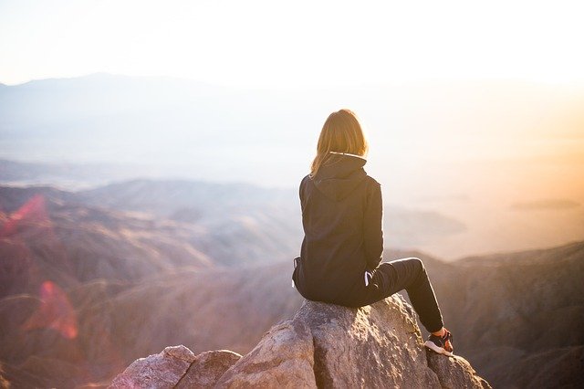 Woman Travel adventure on a mountain sitting on a rock