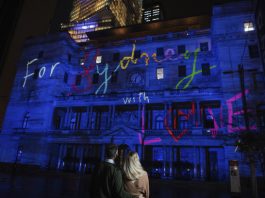 Couple viewing the 'For Sydney With Love' projection on Customs House during Vivid Sydney 2022.