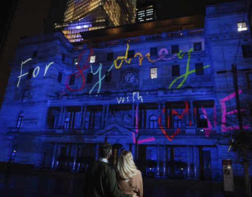 Vivid Sydney Sparkles to Life, Transforming Sydney into a Dazzling Kaleidoscope Of Light Couple viewing the 'For Sydney With Love' projection on Customs House during Vivid Sydney 2022.