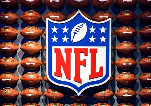 Best places to travel for the NFL season NFL logo on a wall of footballs