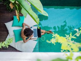 woman working on a laptop while sitting at a pool