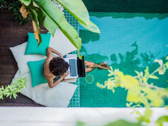 woman working on a laptop while sitting at a pool