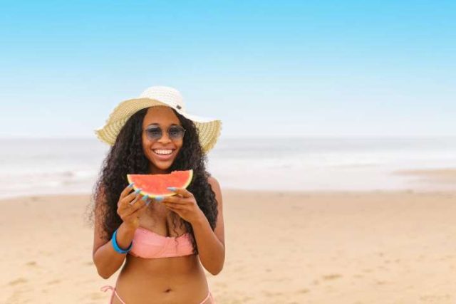 girl on beach eating watermelon