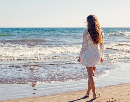 Look And Feel Gorgeous On The Beach With These Outfit Ideas Young Woman Beach Dress White Dress Walking