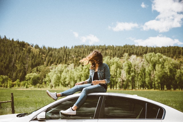 girl sitting on the top of a car