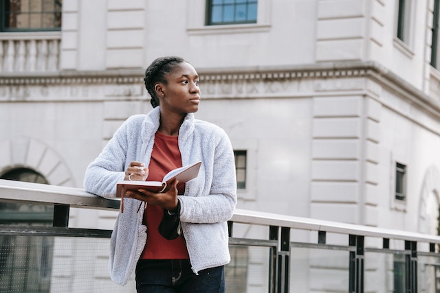 girl reading a book on a bridge