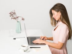 Coming Back To The Office? Here Are Your 9 Must-Have Work Essentials! girl working on a laptop at a desk