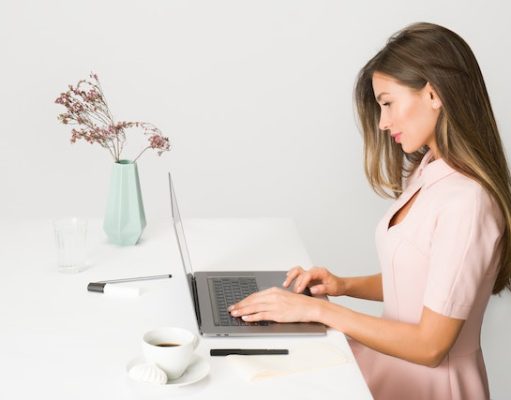 Coming Back To The Office? Here Are Your 9 Must-Have Work Essentials! girl working on a laptop at a desk