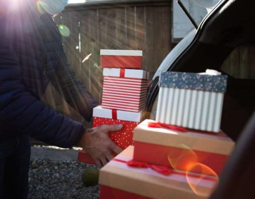 Protect Your Car During The Holidays From Break-Ins man packing Christmas gift boxes in car