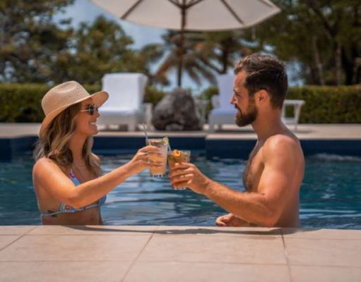 Post Wedding Recovery Package Launched couple having cocktails by a resort pool