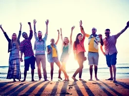 LGBTQ+ travelers on a beach waving