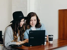 two girls watching travel videos on a laptop