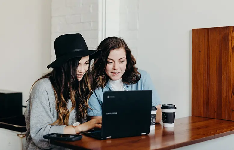 two girls watching travel videos on a laptop
