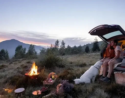 The Ultimate Car Camping Checklist: Pack Your Vehicle Like A Pro couple sitting on the back of their car at a camp fire