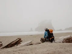 7 Reasons Why You Could (and should) Travel Alone man sitting alone on a foggy beach