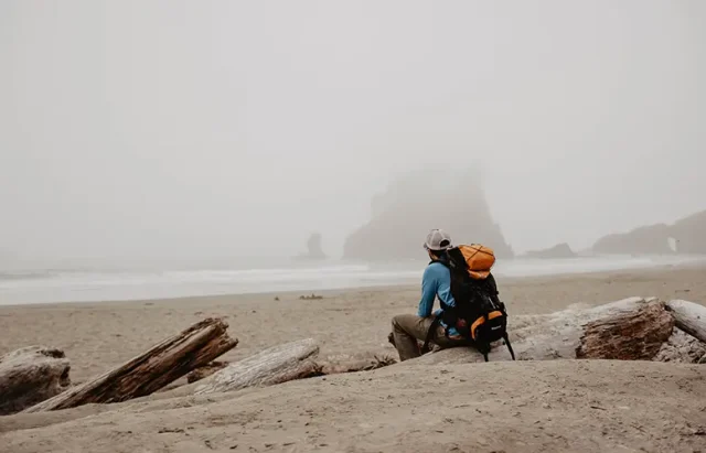man sitting alone on a foggy beach
