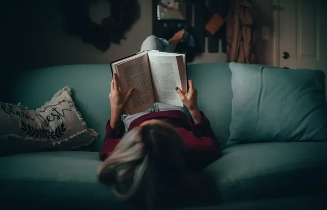 person lying on their back reading a book