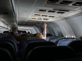 child raising their hand on passenger seat of a plane