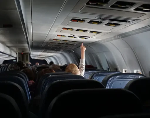 How to Keep Your Children Safe on Family Trips child raising their hand on passenger seat of a plane