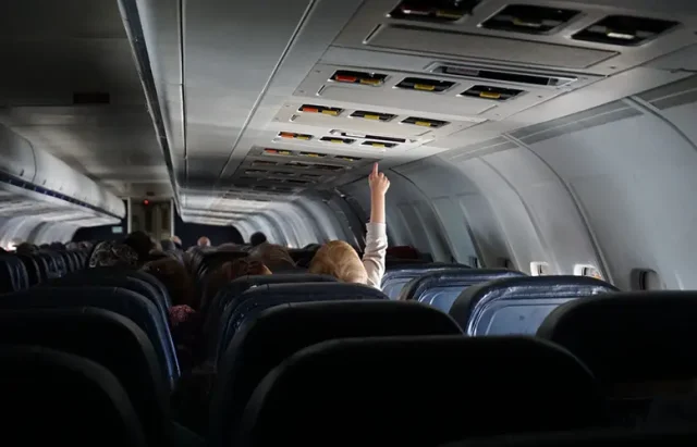 child raising their hand on passenger seat of a plane