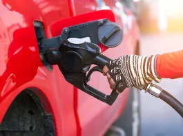 worker hand holding nozzle for filling diesel fuel into red pick up car at refuel station