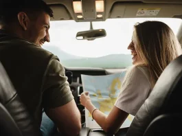 Young loving couple on a road trip using map inside a car