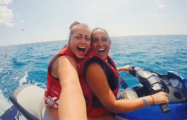 lesbian couple on vacation doing water sports on jet ski in ocean