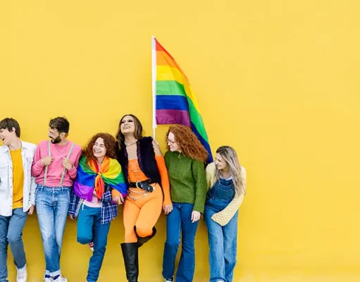 Greater Miami LGBTQ+ Chamber Of Commerce Launches Pink Flamingo Hospitality Initiative Young group of people leaning on yellow background celebrating together LGBTQI gay pride festival day. LGBT young friends having fun together outdoors.