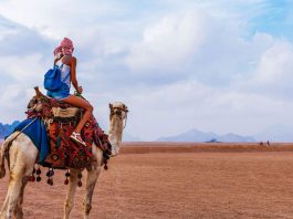 Tourist woman in traditional arabian clothes with camel in the Sinai Desert, Sharm el Sheikh, Sinai Peninsula, Egypt