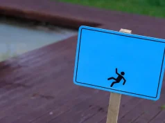 Proving Negligence in Slip and Fall Cases: Key Elements to Consider caution wet floor warning sign near swimming pool in hotel.