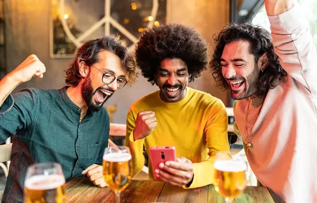 Three excited multiracial friends celebrating winning online bet on match